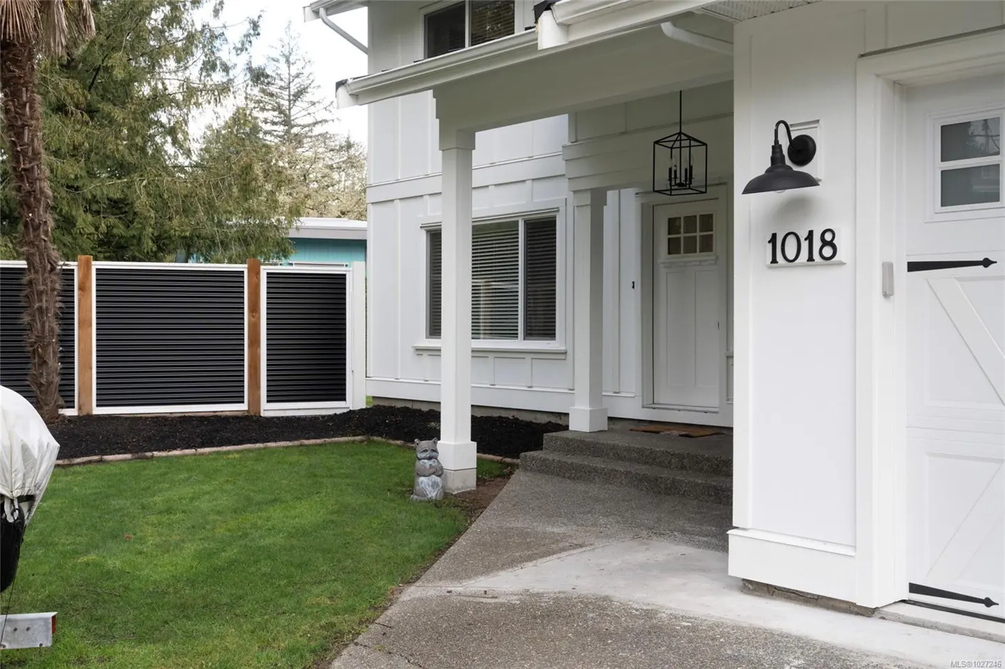 Exterior of a white house with a black fence, green lawn, and the address number 1018.