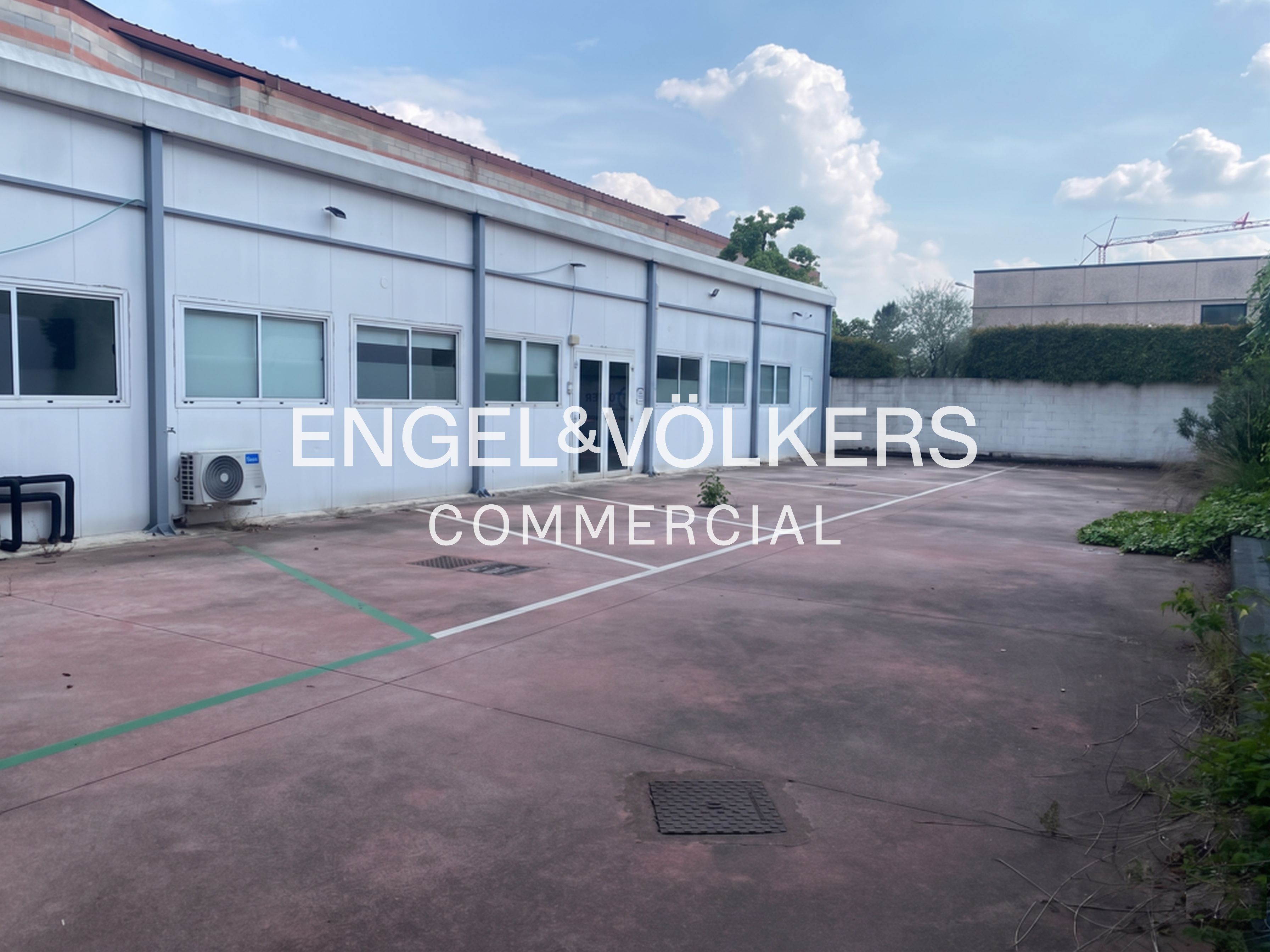 Exterior of a white commercial building with a large parking lot and Engel & Völkers logo.