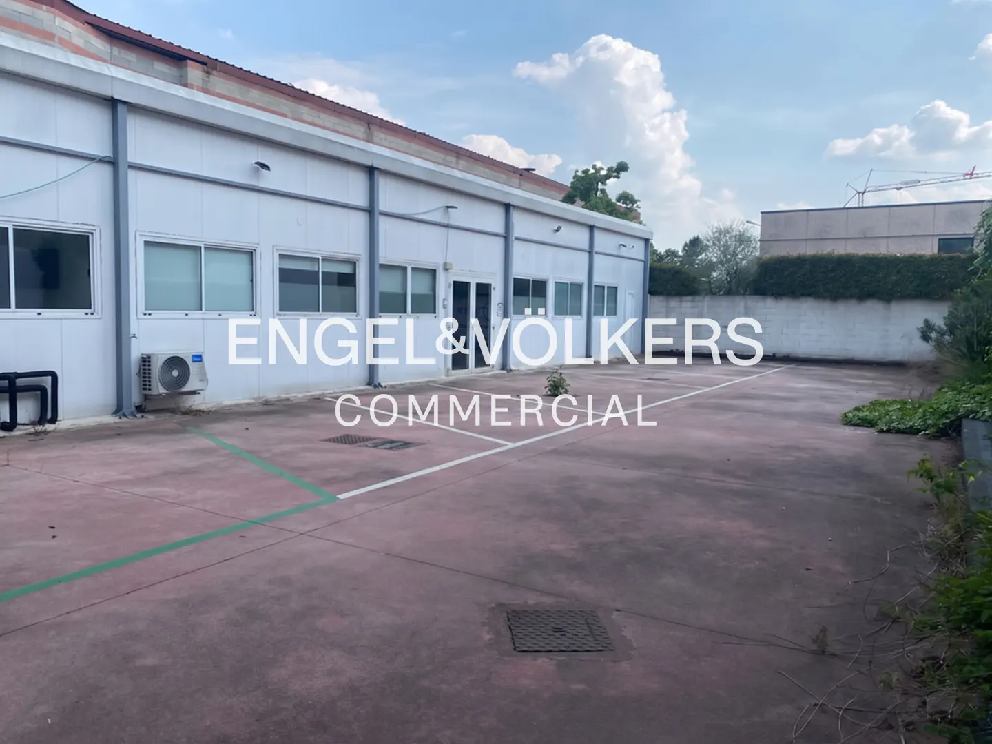 Exterior of a white commercial building with a large parking lot and Engel & Völkers logo.