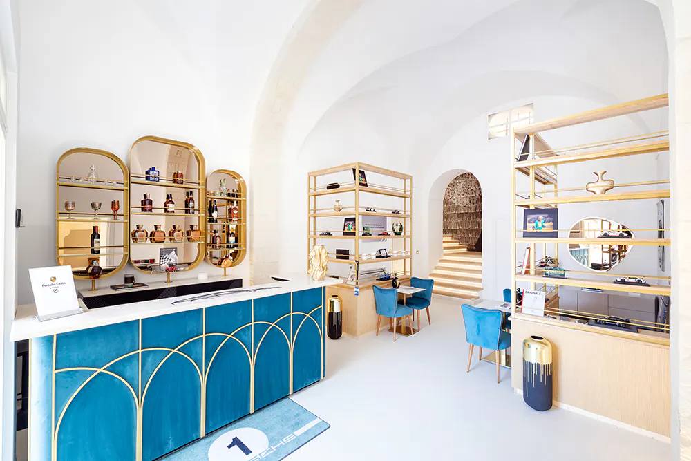 Bright, modern store interior with white walls, arched ceiling, blue counter with gold trim, and shelves displaying merchandise.
