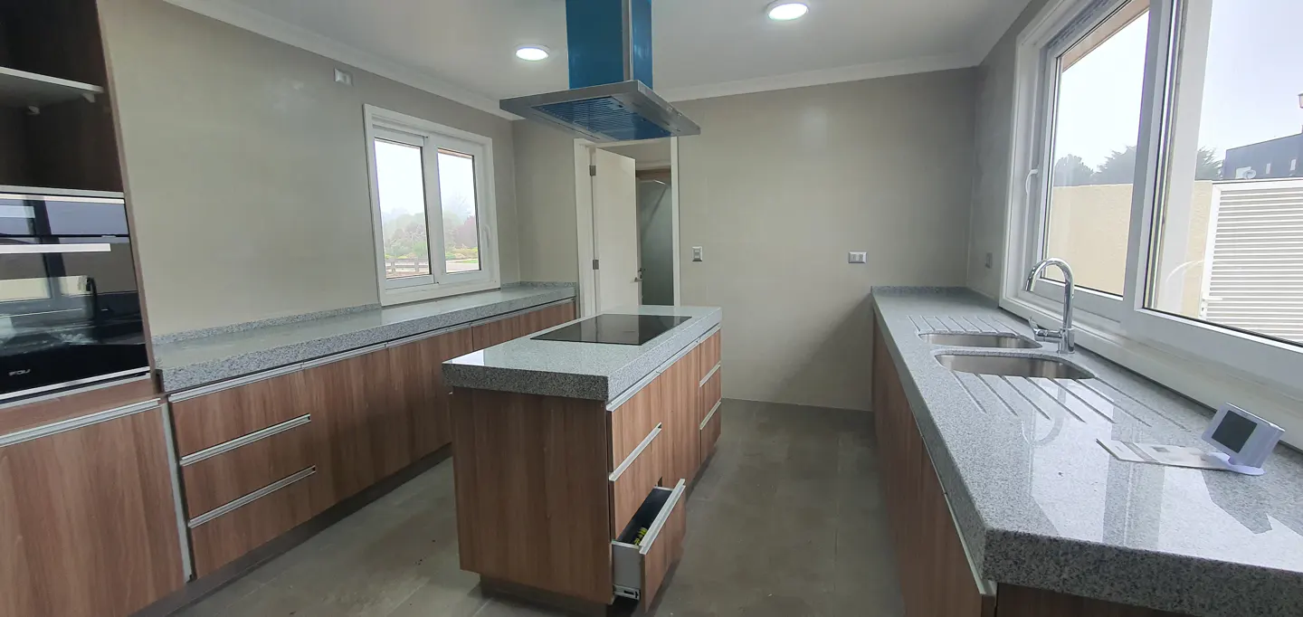 Bright kitchen with wood cabinets, granite countertops, and stainless steel appliances. A kitchen island sits in the center of the room.