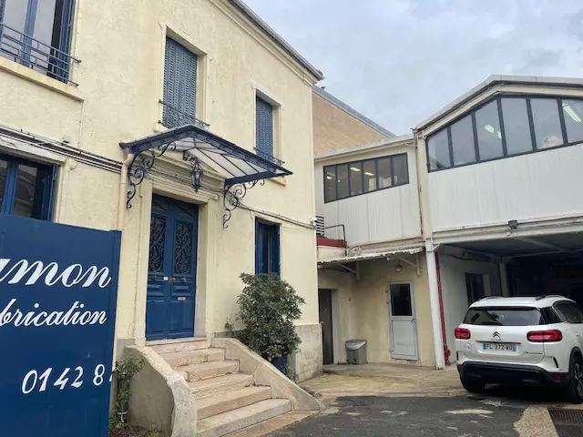 Two-story building with a blue door and awning, and a white car parked in a garage.