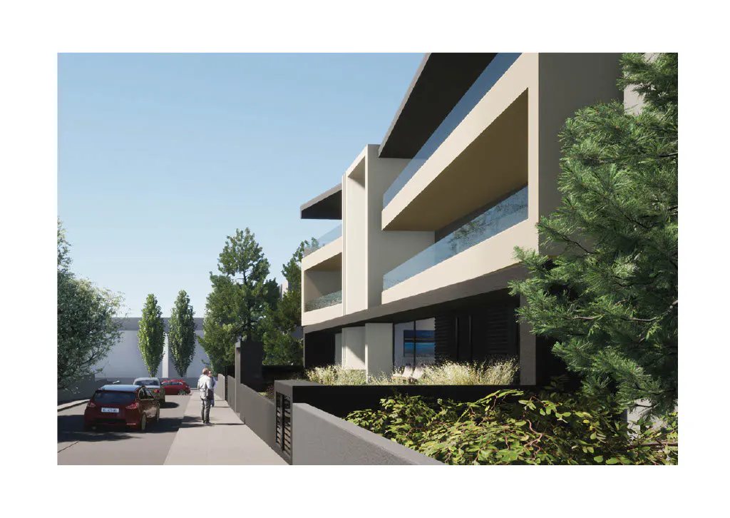 Modern apartment building with balconies, set back from the street. Cars and a person walking on the sidewalk are visible.