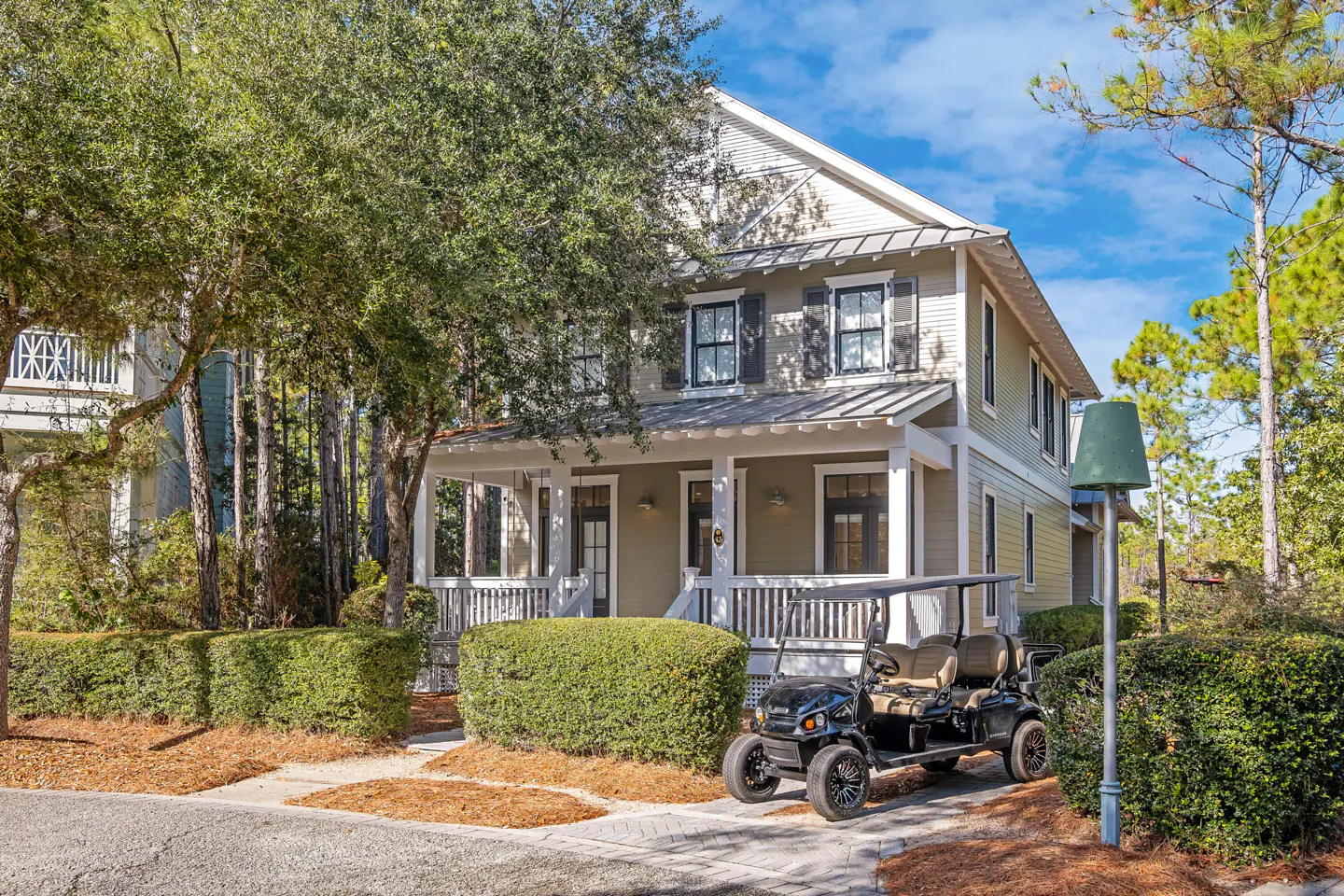 Two-story house with a front porch, black shutters, and a golf cart parked in the driveway.