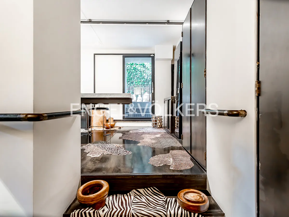Interior view of a modern home with black doors, a zebra-print rug, and a view to the outside.