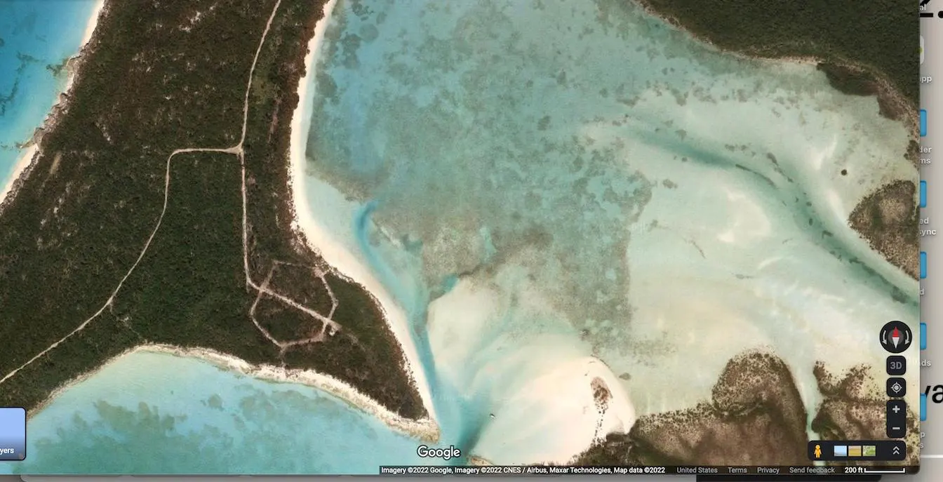 Aerial view of a tropical island with turquoise water and sandy beaches. Lush green vegetation covers part of the island.