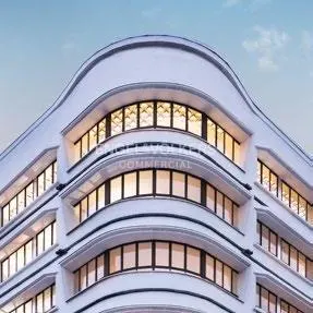 Exterior of a white commercial building with curved facade and rows of windows under a blue sky.