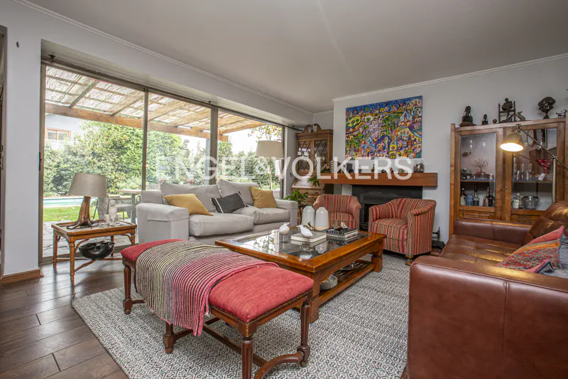 Living room with a gray sofa, red striped chairs, and a brown leather sofa. A colorful painting hangs above the fireplace.