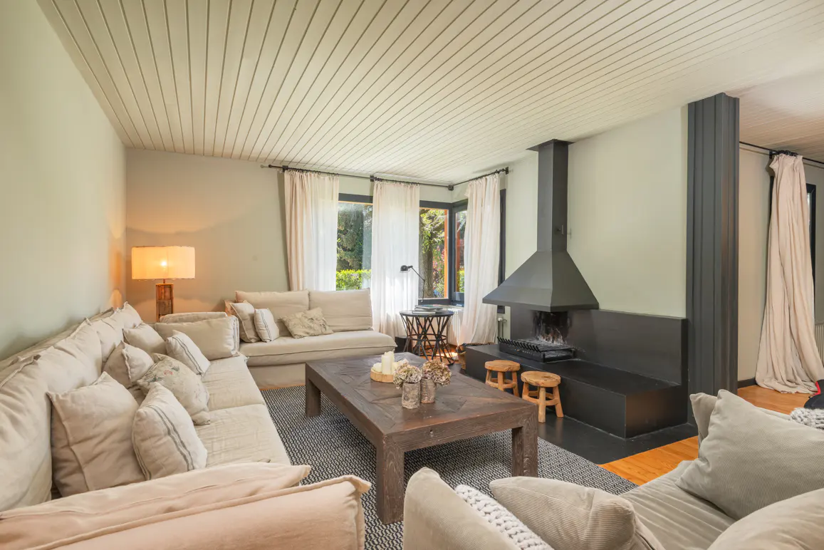Living room with a large beige sectional sofa, dark wood coffee table, and a black fireplace with a tall chimney.