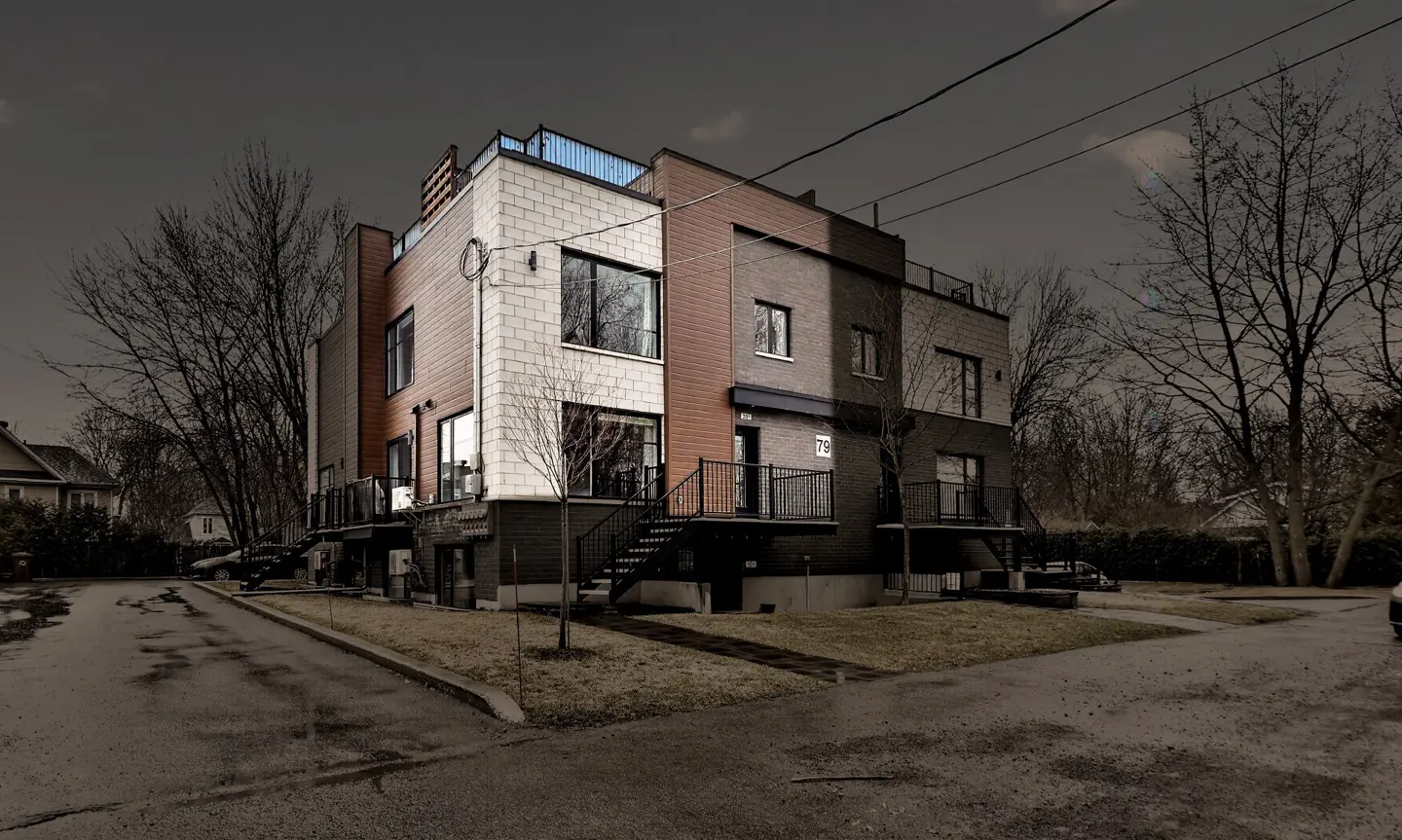 Exterior view of a modern three-story townhouse with brick and wood paneling, black metal stairs, and a rooftop deck.