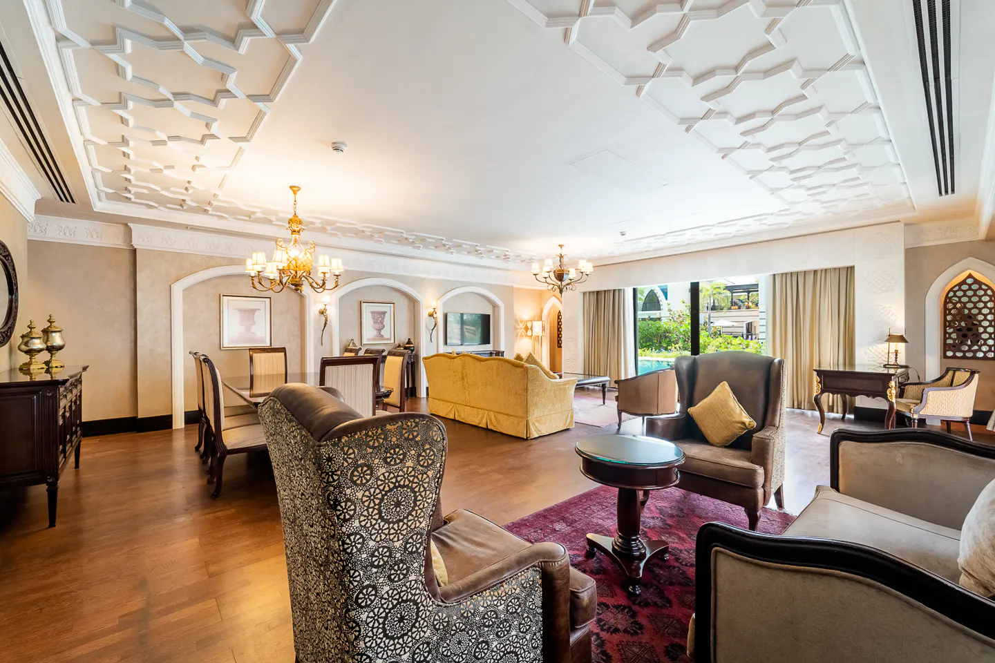 Opulent living room with patterned chairs, a yellow sofa, and a decorative ceiling with chandeliers.
