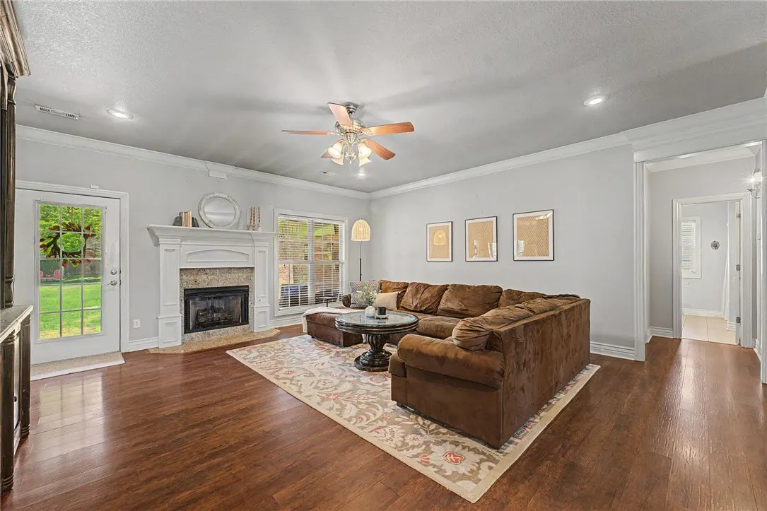 Living room with brown sectional sofa, fireplace, and hardwood floors. Neutral rug and wall art add warmth to the space.
