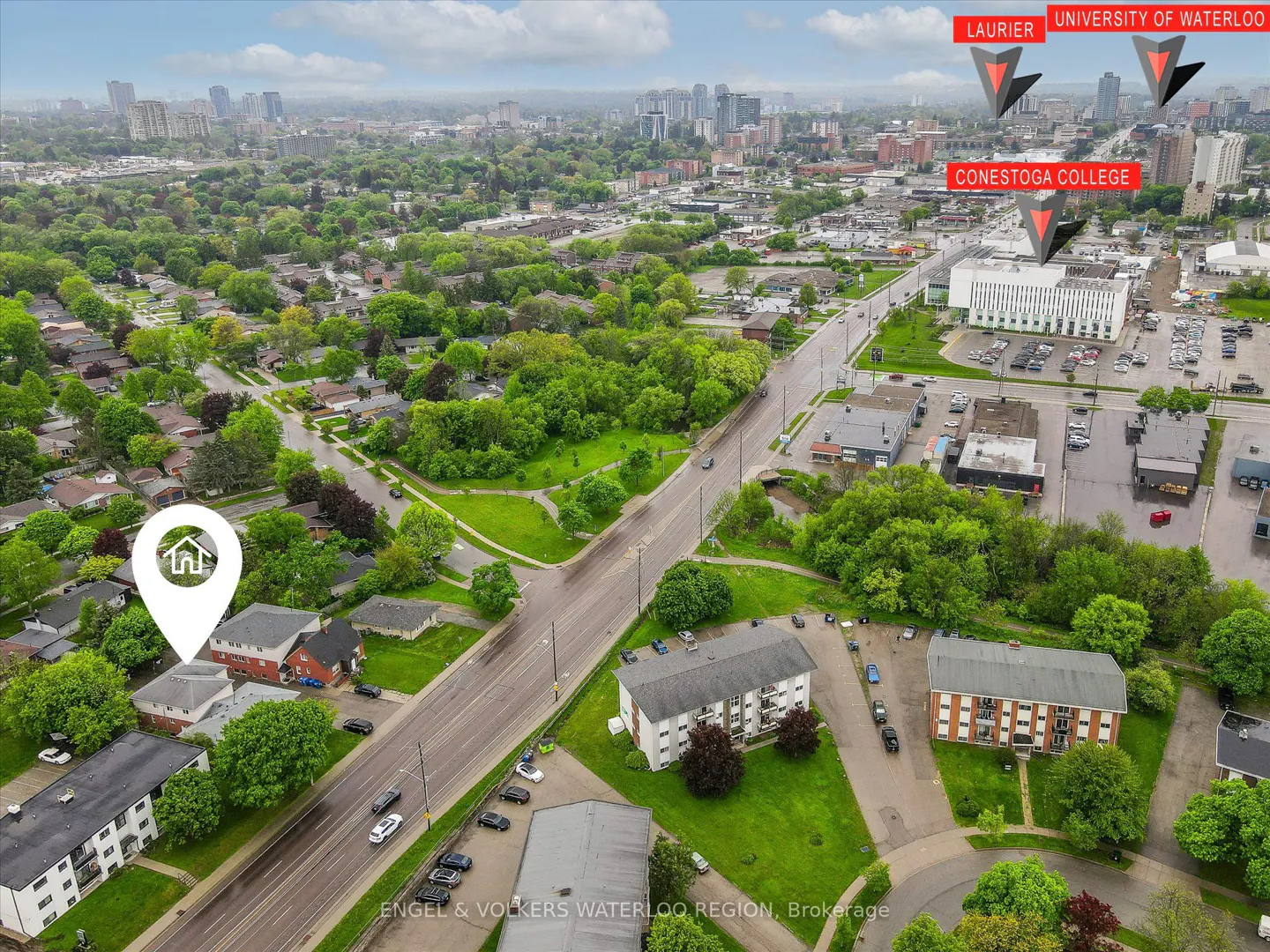 Aerial view of a property in Waterloo, Ontario, near Laurier, University of Waterloo, and Conestoga College. The area is lush with trees and buildings.