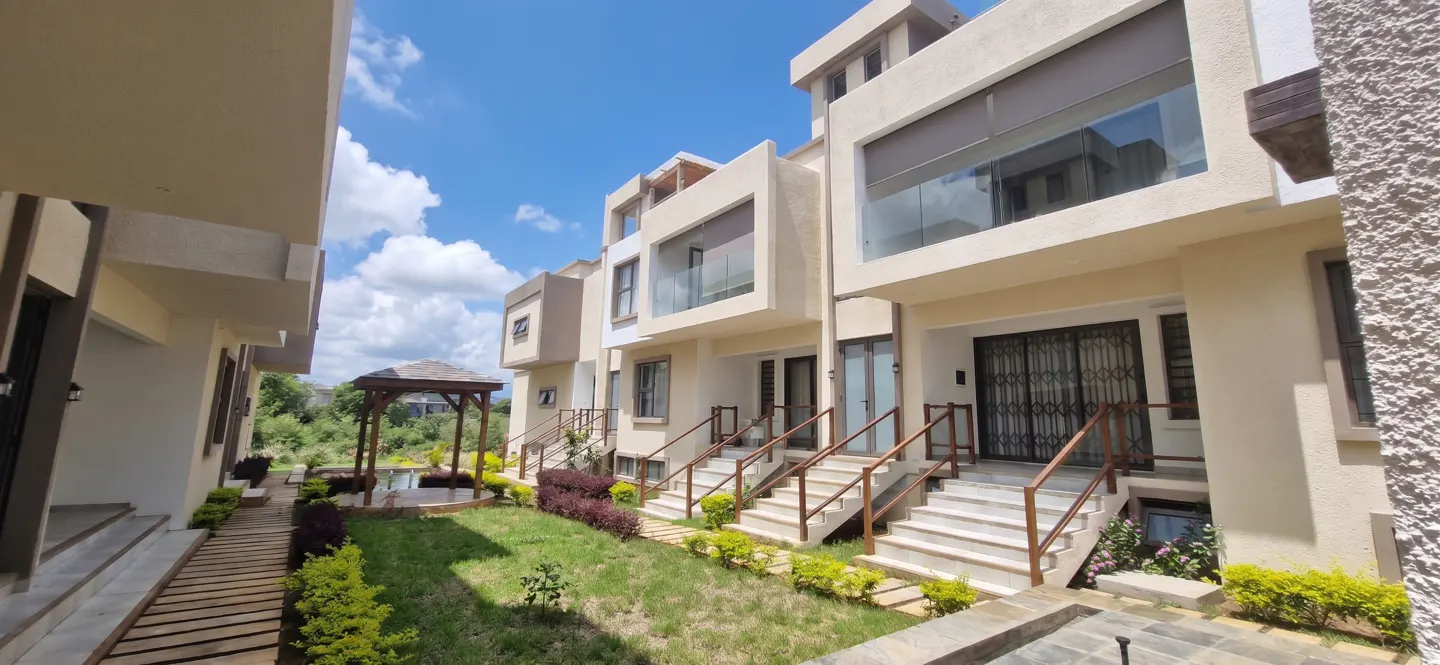 Exterior view of modern townhouses with stairs leading to each entrance, a gazebo, and a blue sky.