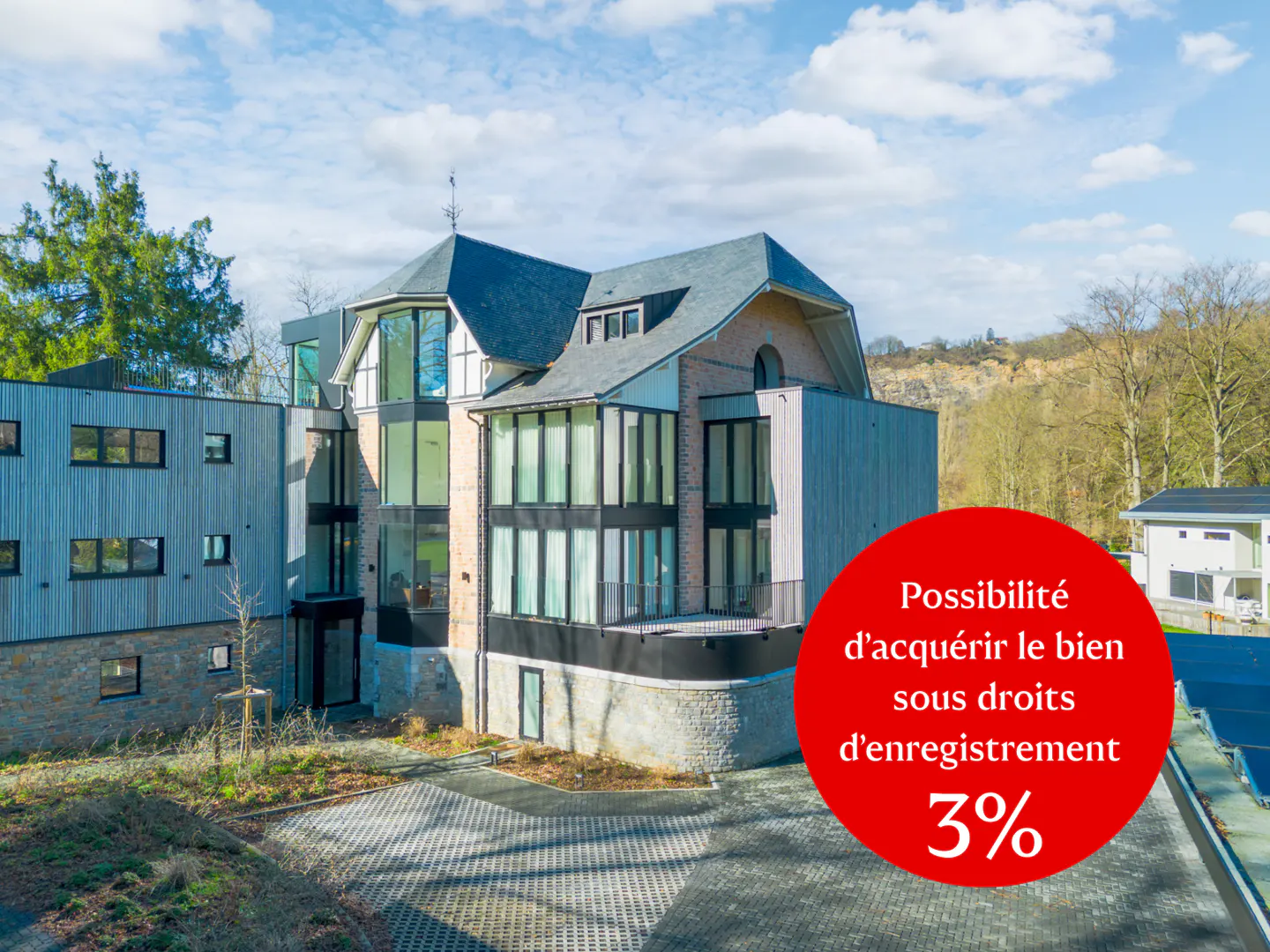 Exterior of a modern house with large windows and gray siding under a blue sky. A red circle advertises a 3% registration fee.
