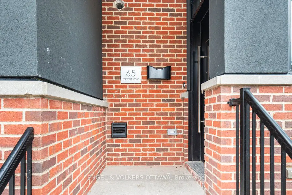 Exterior view of 65 Parent Ave. with red brick, black accents, and a modern mailbox. Black railings lead to the front door.