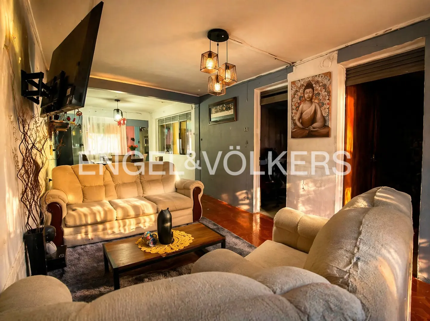 Living room with beige sofa, armchair, and wood coffee table on a gray rug. A Buddha painting hangs on the wall.