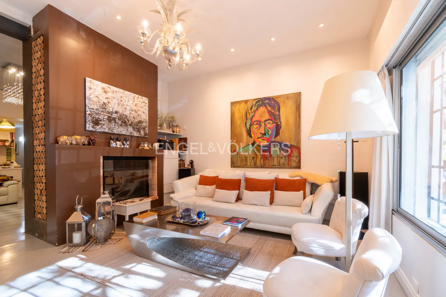 Living room with white sofa, chairs, and a metal coffee table on a rug. A large painting hangs above the sofa.