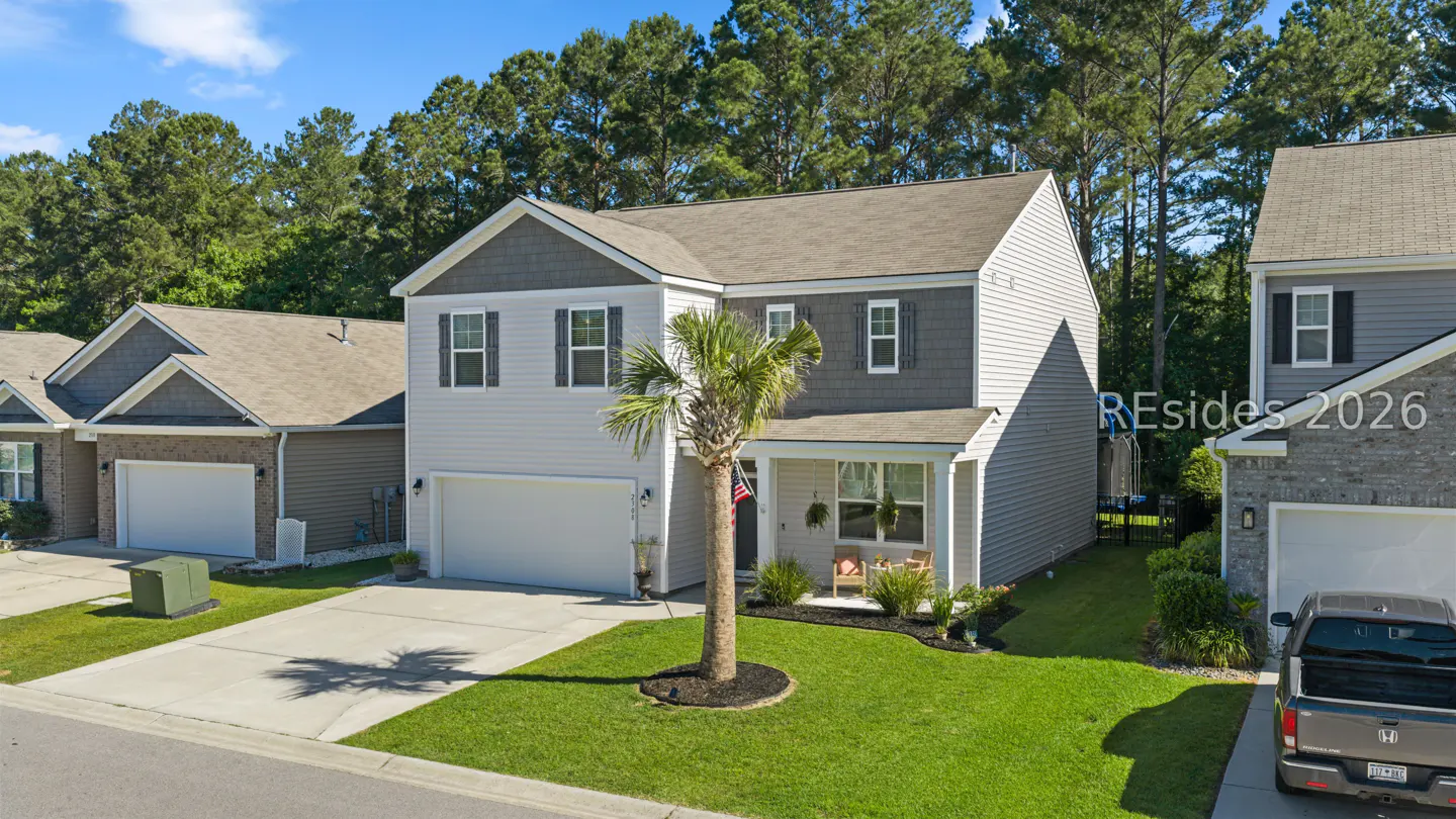 Two-story house with white siding, gray trim, and a palm tree in the front yard. A truck is parked in the driveway next door.