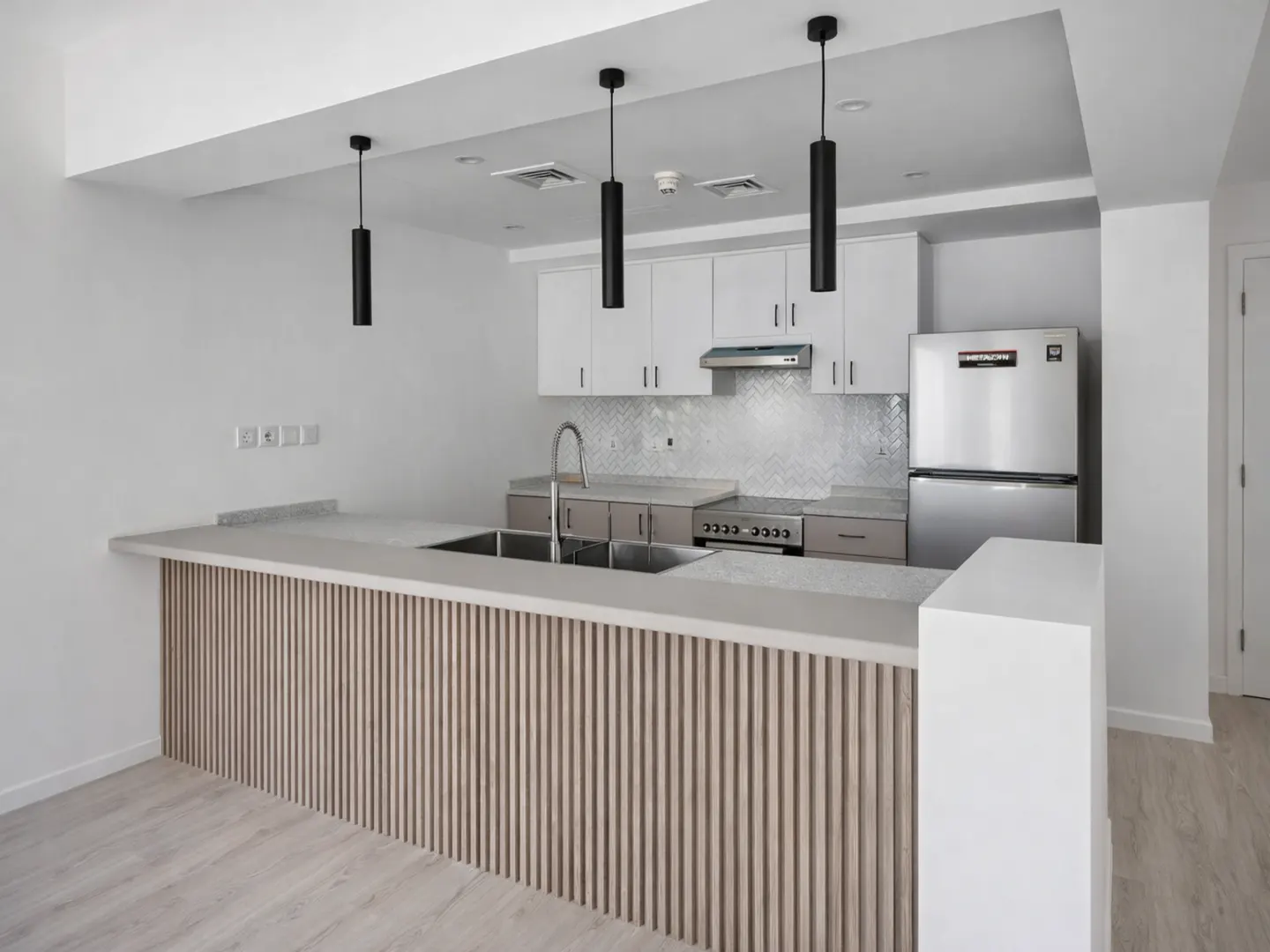 Modern kitchen with white cabinets, stainless steel appliances, and a wood-slatted breakfast bar with black pendant lights.