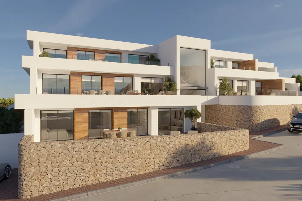 Modern white multi-story home with wood accents, large windows, and stone retaining wall on a sunny day.