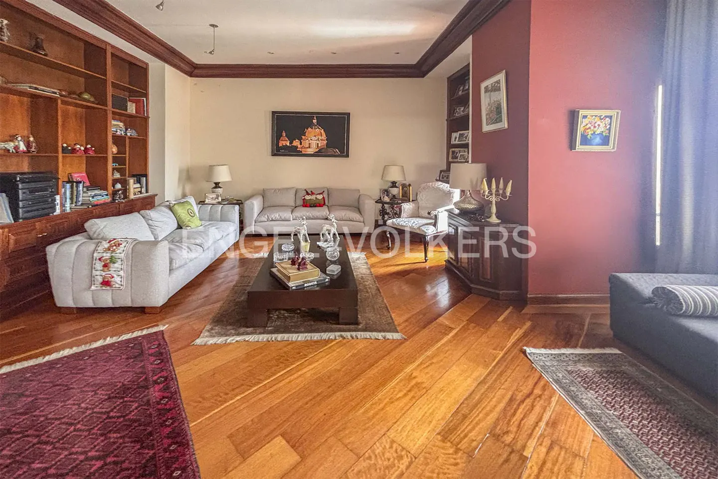 A living room with hardwood floors, sofas, a coffee table, and built-in bookshelves.