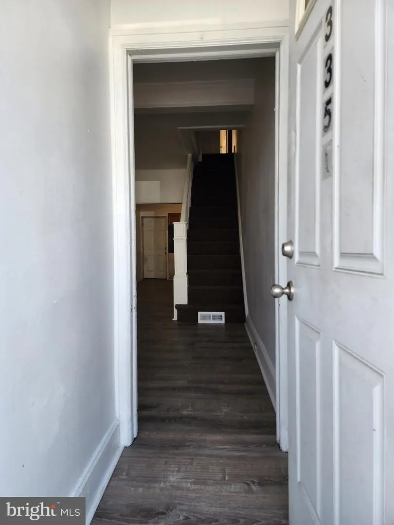 Open white front door with the number 335, leading to a hallway with stairs and wood-look flooring.