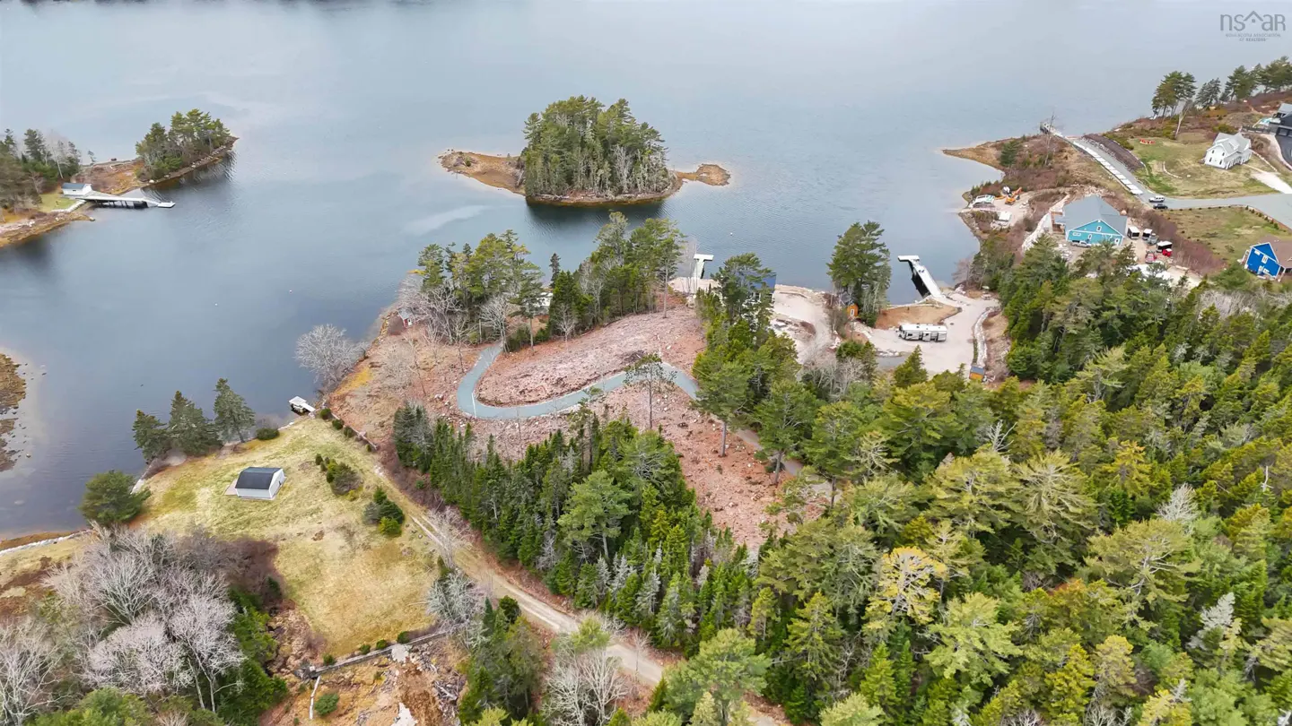 Aerial view of a wooded waterfront property with a winding gravel path, docks, and small islands in a dark blue lake.
