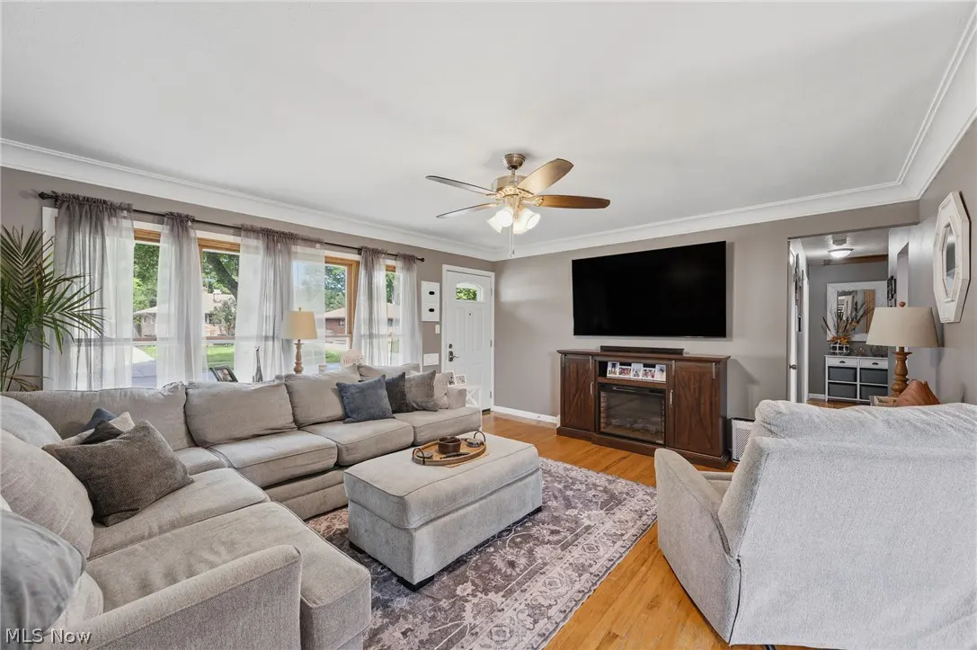 Living room with gray walls, hardwood floors, and a large gray sectional sofa. A TV is mounted above a wooden console.