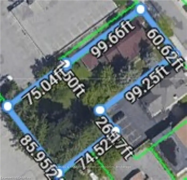 Aerial view of a property outlined in blue with dimensions in feet. Buildings, trees, and parking are visible within the property lines.