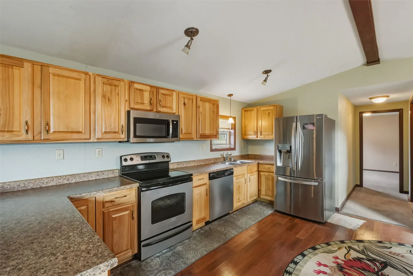 A kitchen with light wood cabinets, stainless steel appliances, and a dark countertop.