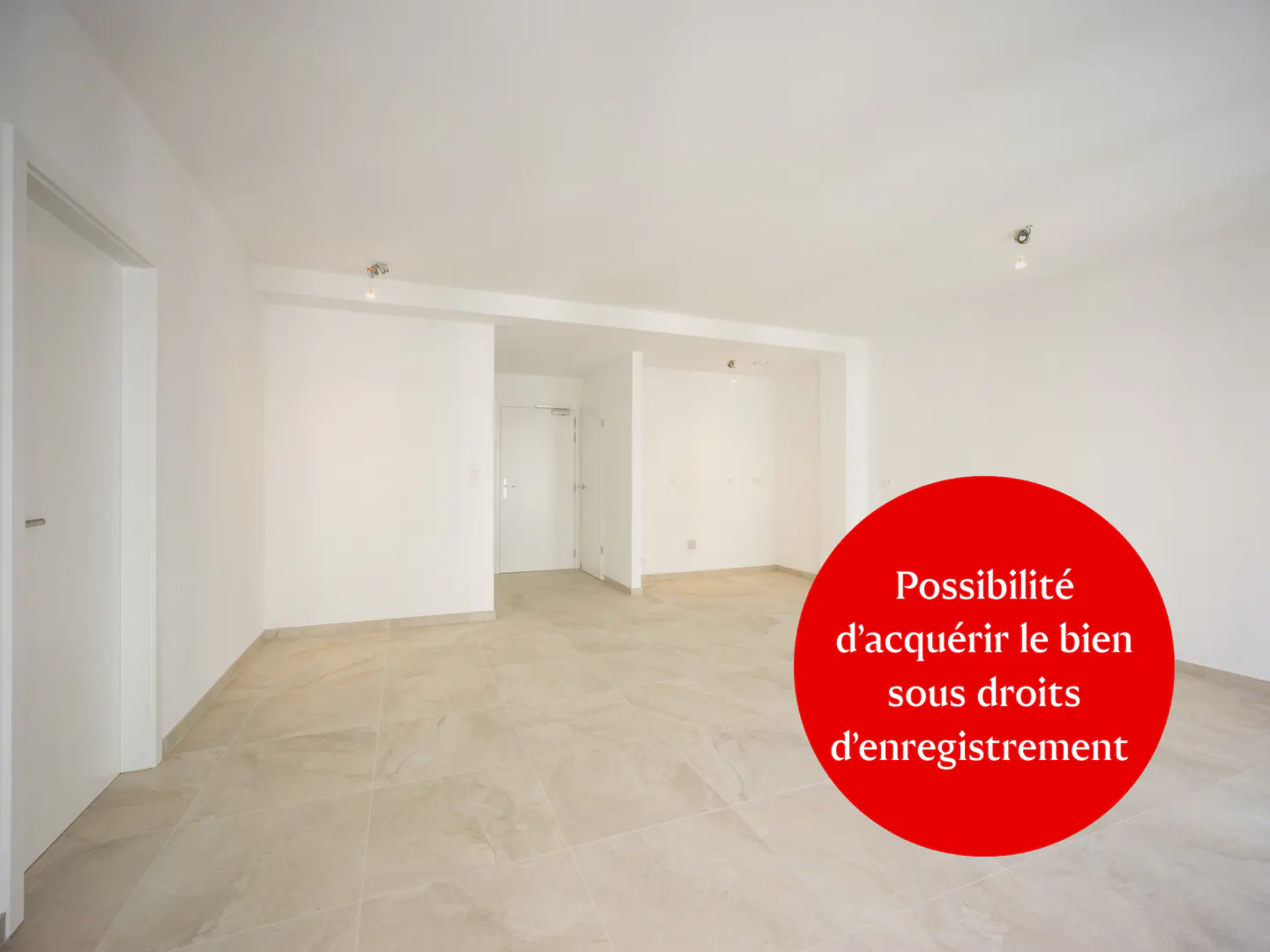 Bright, empty room with white walls and beige tile floor. A red circle with white text in French is superimposed on the image.