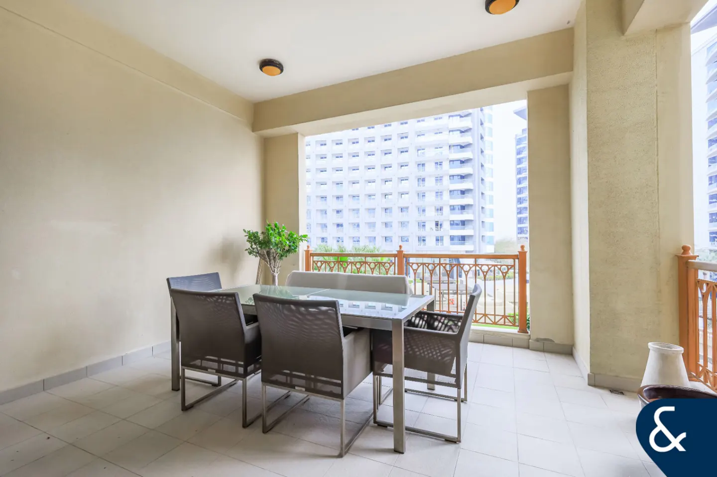 A balcony with a dining table set and a view of a tall building.