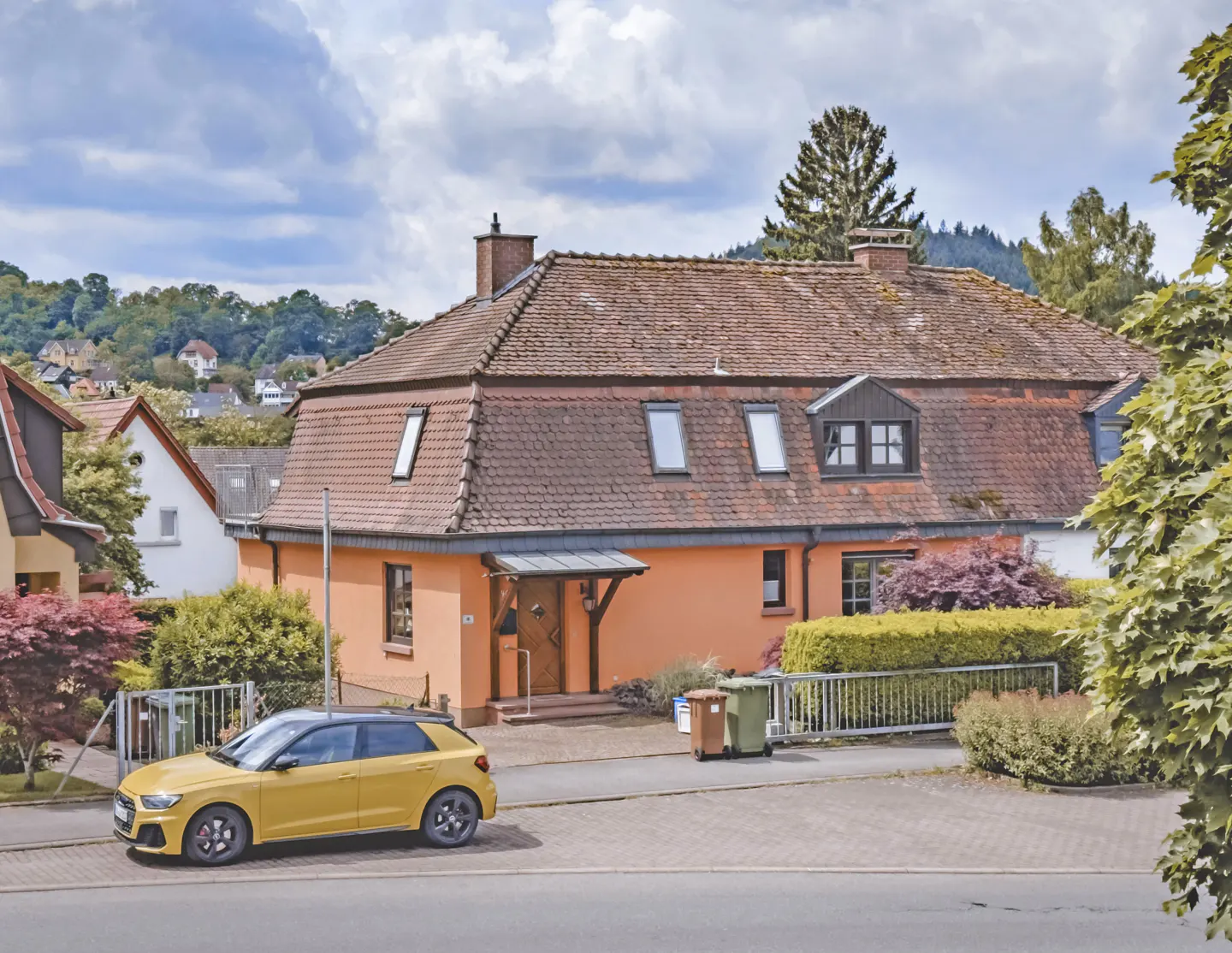 Exterior view of a peach-colored house with a brown roof and a yellow car parked in front.