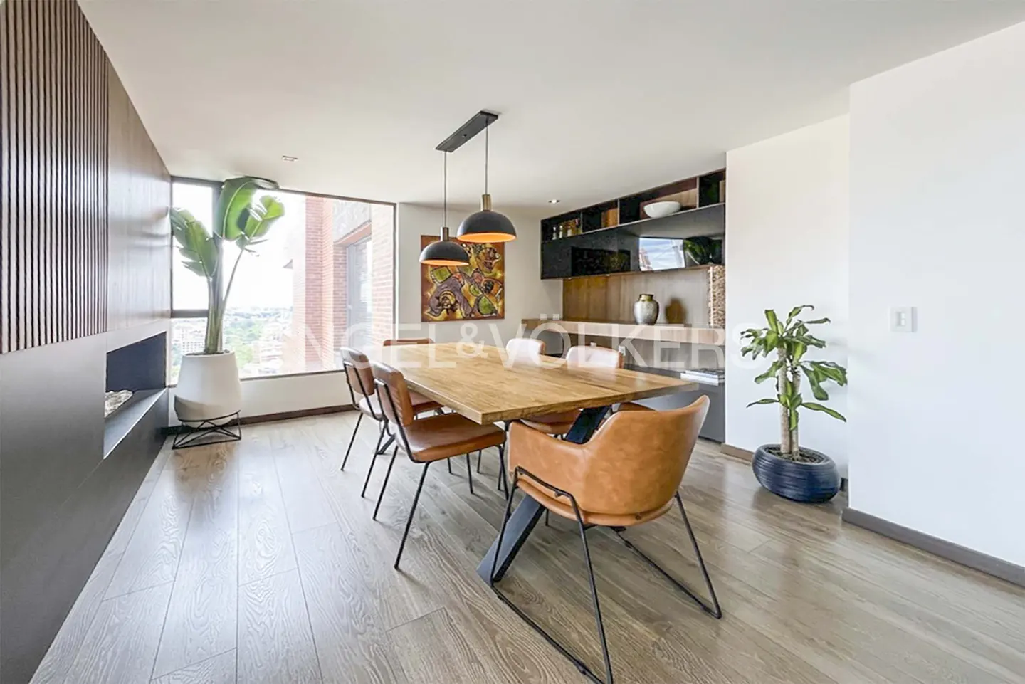 Bright dining room with a wood table, leather chairs, and black pendant lights. A large window offers a city view.