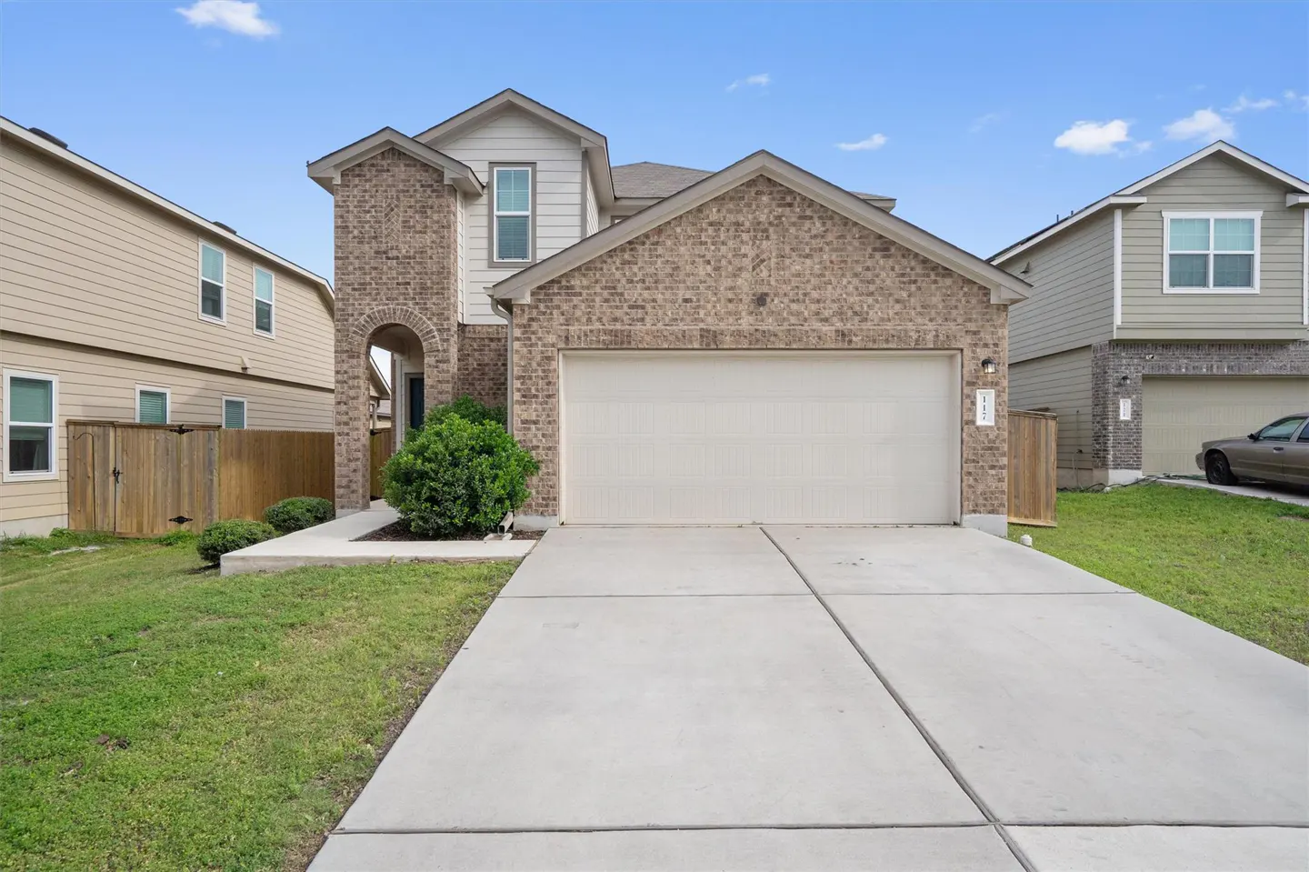 Two-story brick and siding home with a two-car garage and a concrete driveway on a sunny day.
