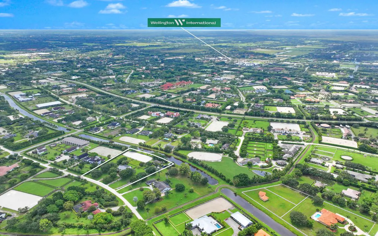 Aerial view of a property in Wellington, Florida, with green lawns, trees, and a white outline marking the property lines.