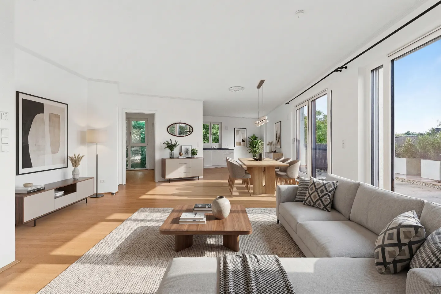 Bright, open-concept living and dining area with light wood floors, a beige sectional sofa, and a wooden dining table.