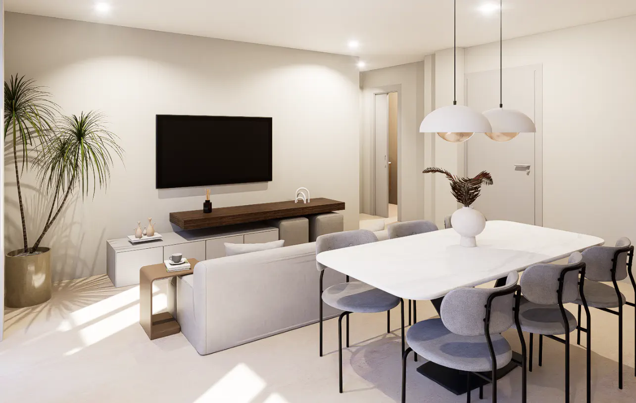 Bright living and dining area with a white sofa, TV, and a white table with six gray chairs. Two pendant lights hang above the table.