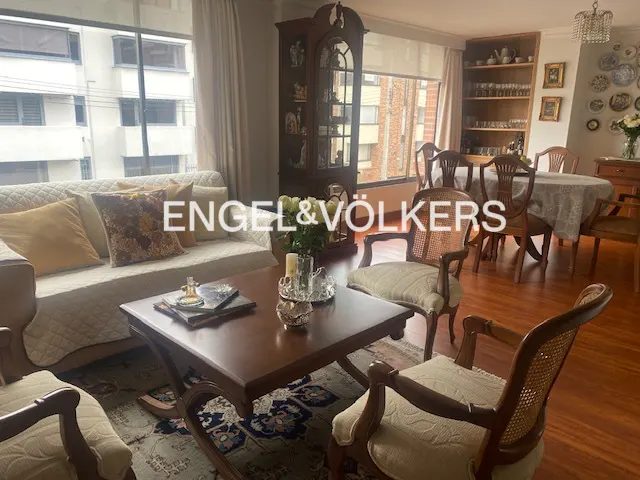 Living room with a sofa, wooden chairs, a coffee table, and a dining area with a round table.
