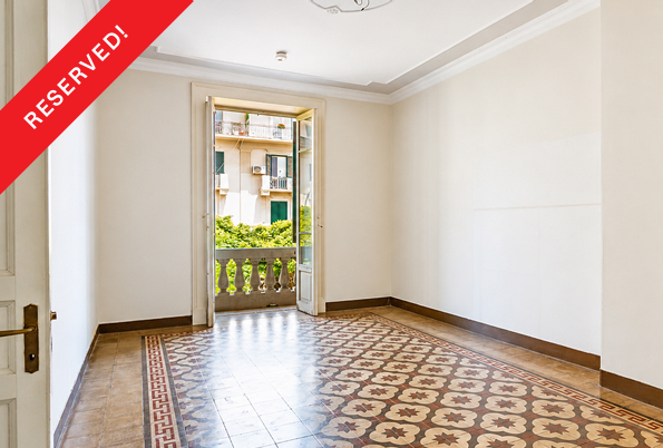 Empty room with patterned tile floors and a balcony door overlooking a building exterior, marked with a Reserved banner.