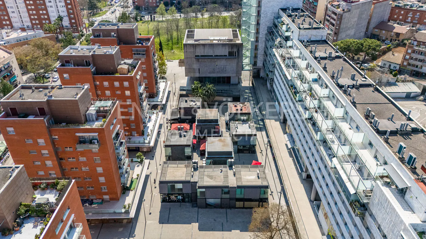 Aerial view of modern architecture featuring brick apartments, a concrete building, and smaller commercial spaces.