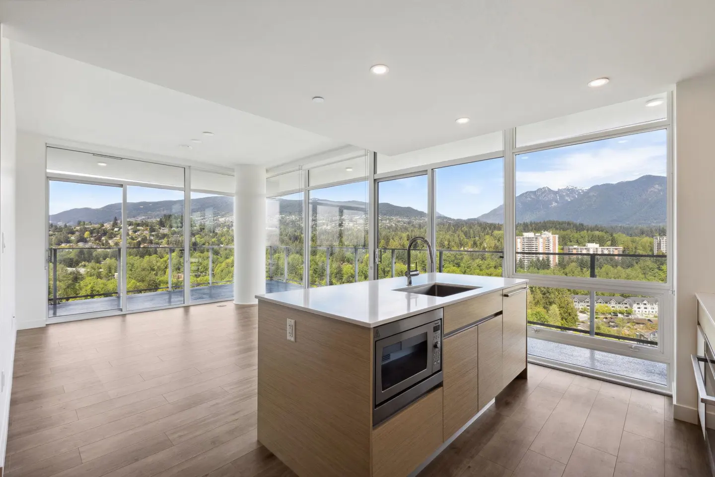 Bright, modern kitchen with wood floors, island, and floor-to-ceiling windows showcasing a mountain view.