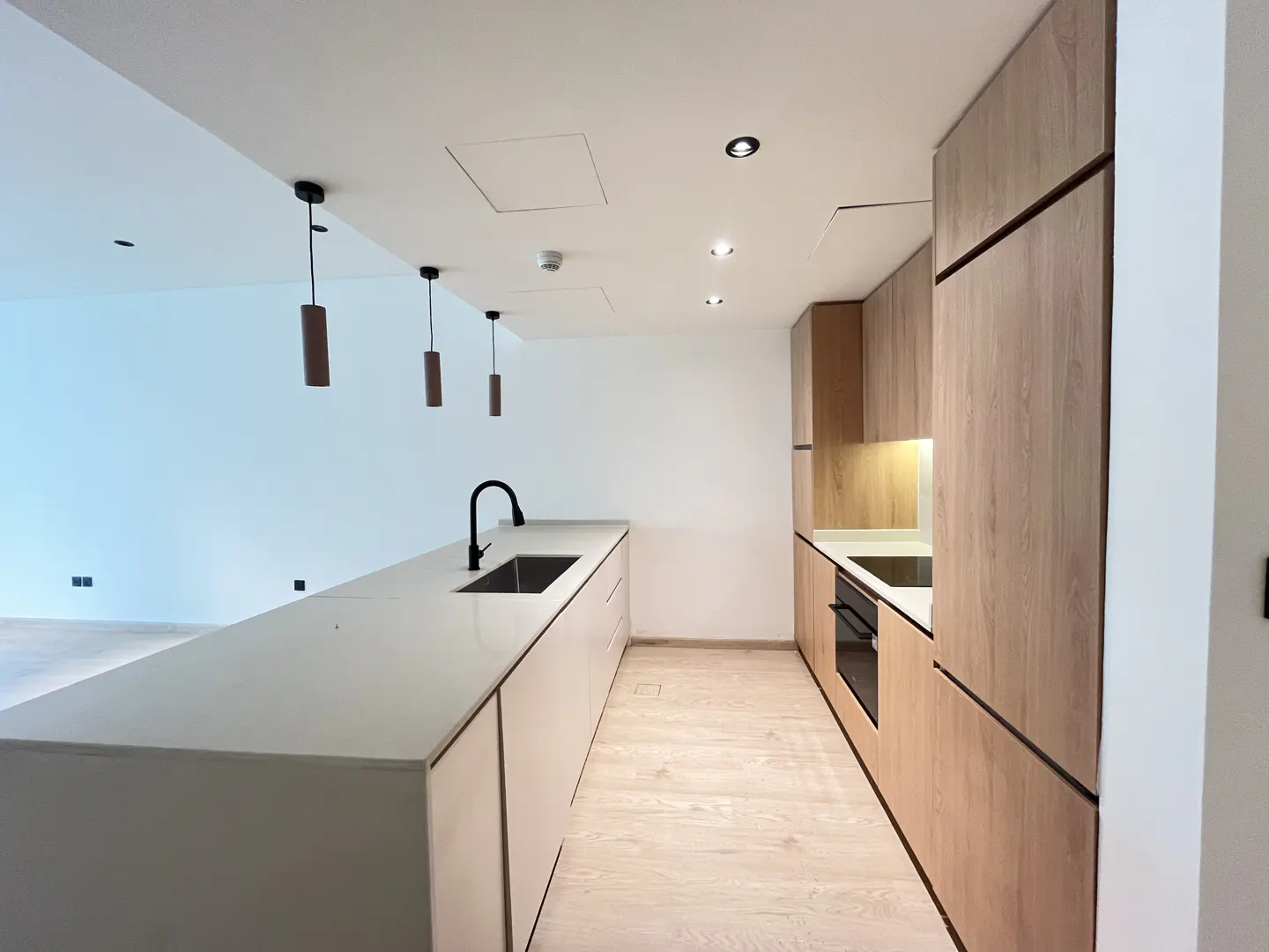 Modern kitchen with a white island, black faucet, wood-tone cabinetry, and three pendant lights over the counter.