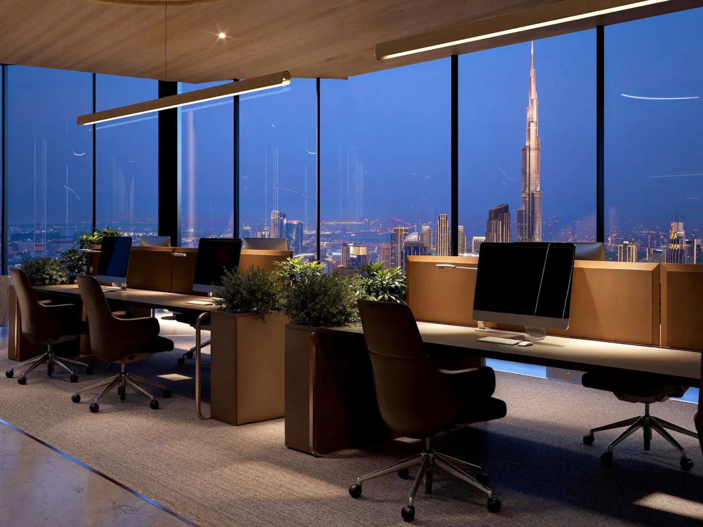 Modern office with desks and computers overlooking the Burj Khalifa and Dubai skyline at twilight.