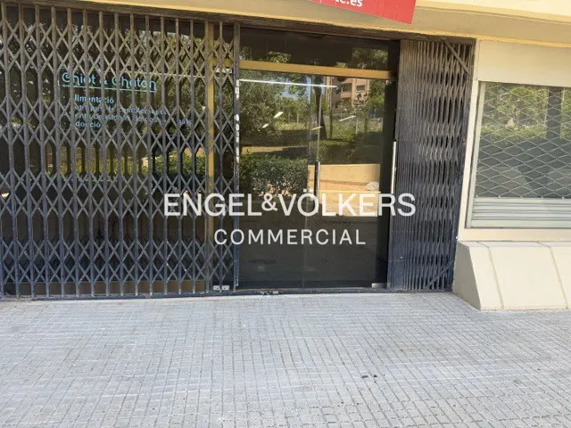 Storefront with a closed metal security gate, glass door, and Engel & Völkers Commercial branding on the window.