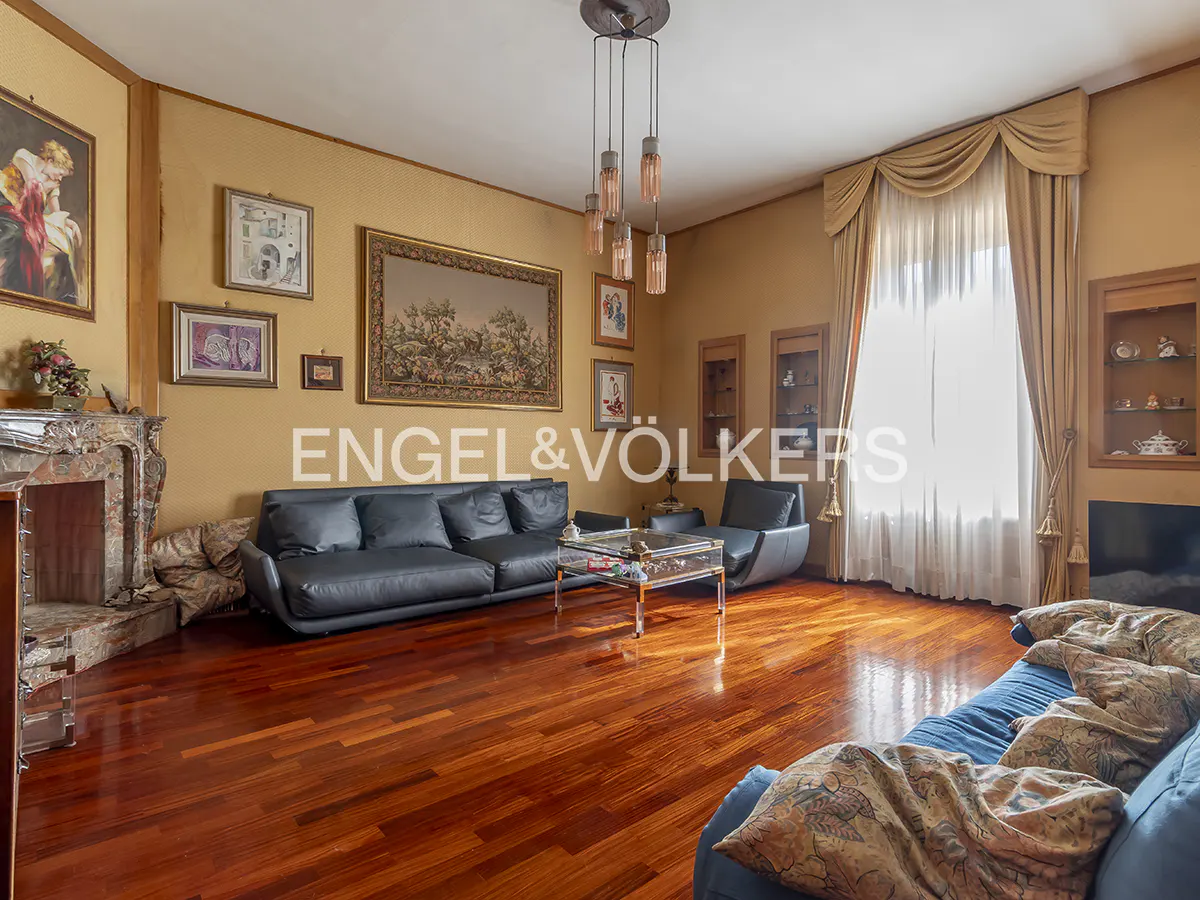 A living room with hardwood floors, a black leather sofa, and a blue sofa.