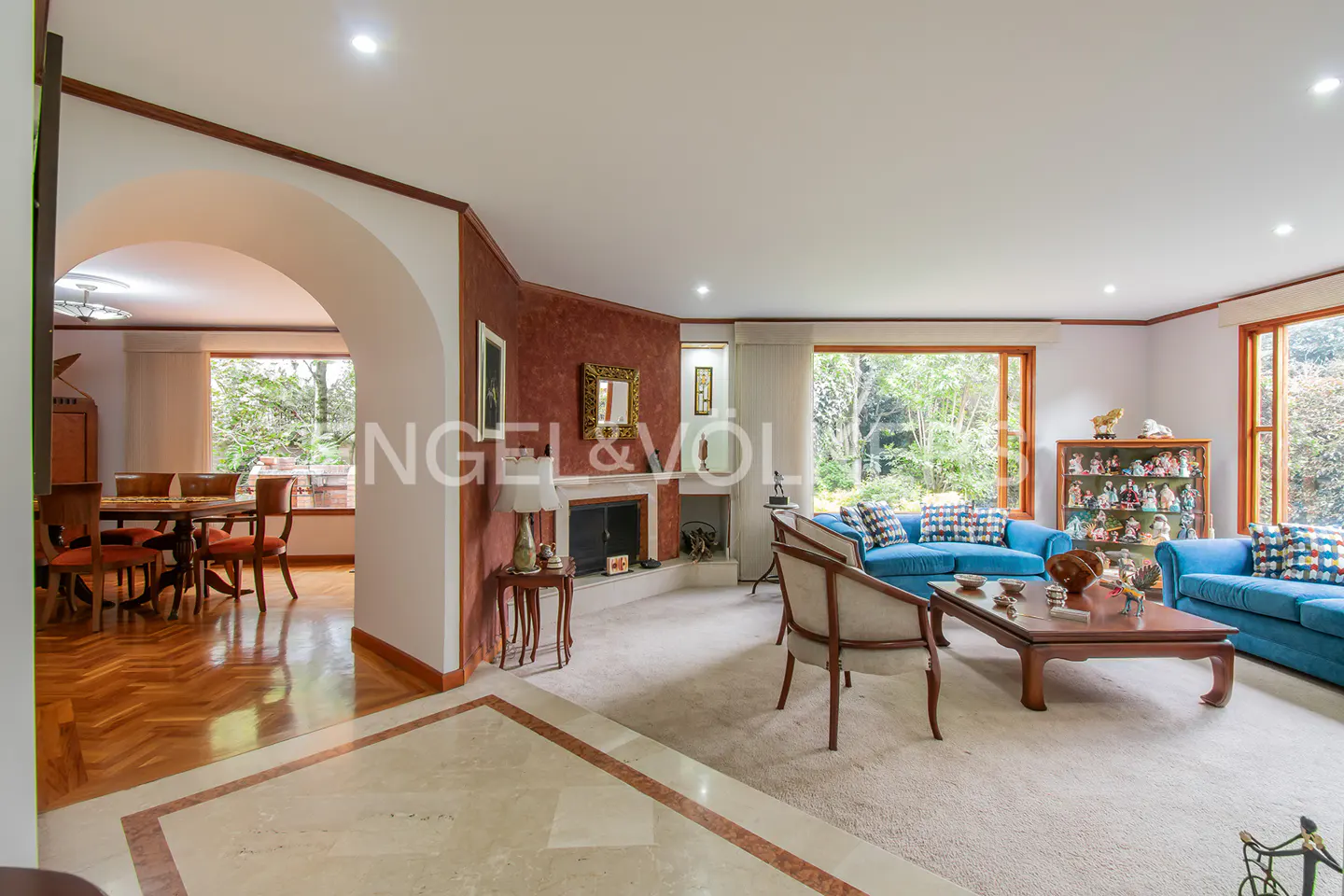 Open-concept living room with blue sofas, a fireplace, and a dining area with a wooden table and chairs.