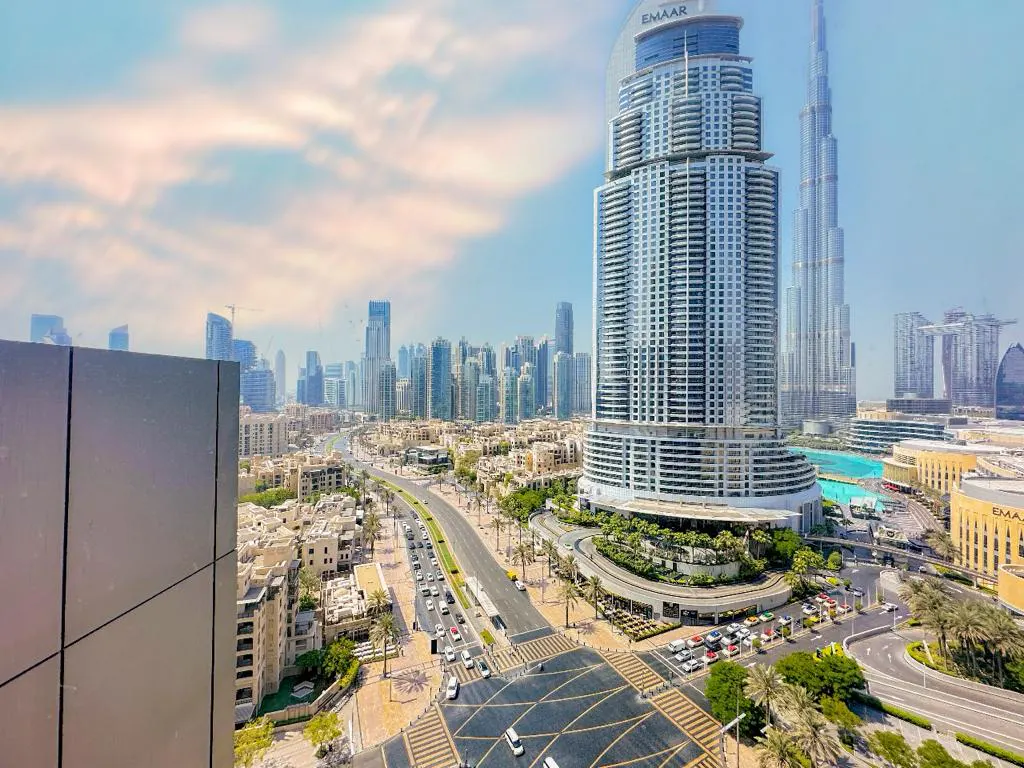 High-angle view of the Dubai skyline featuring the Burj Khalifa and Emaar tower above a busy street with light traffic.