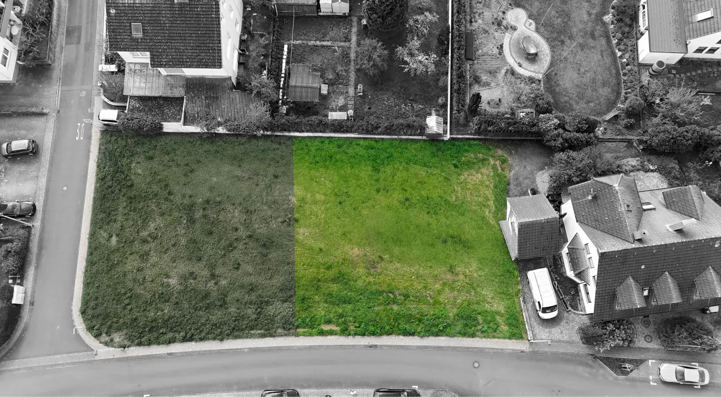 Aerial view of a green lot in a black and white neighborhood, showcasing real estate potential.